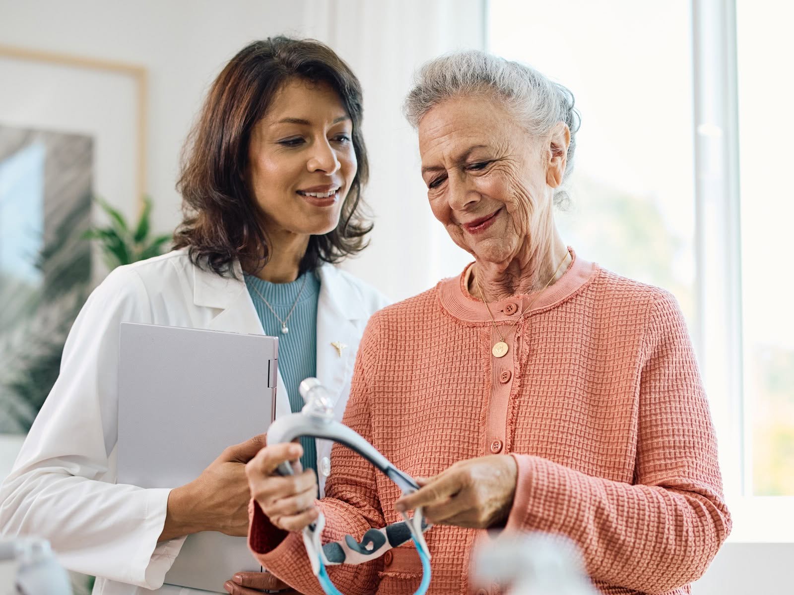 Sleep clinician showing a ResMed CPAP mask to a patient during a fitting